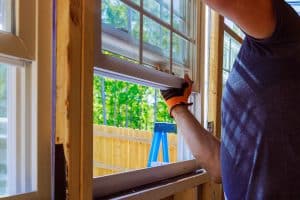 Technician installing a new energy-efficient replacement window in a residential home.